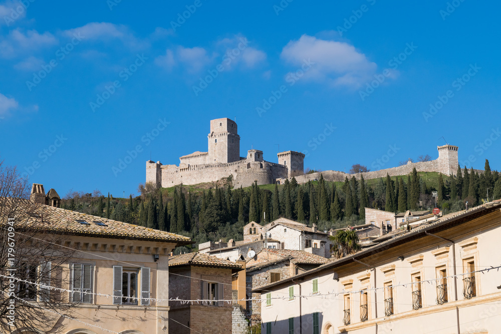 View of the Rocca Maggiore Fortress over the rooftops of Assisi, Umbria, Italy