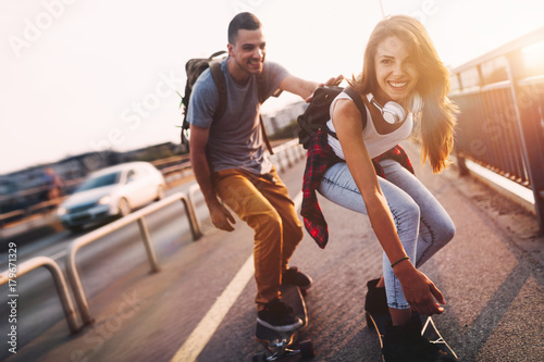Young attractive couple riding skateboards and having fun