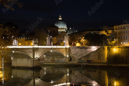 Illuminated Ponte Vittorio Emanuele II bridge at night with the dome of St Peter's Basilica in the distance, in Rome, Italy
