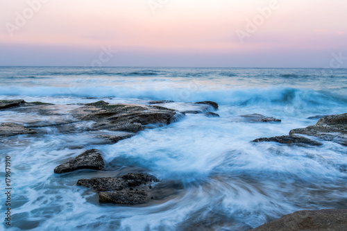 Flwo of wave around the rocks with hazy sky.