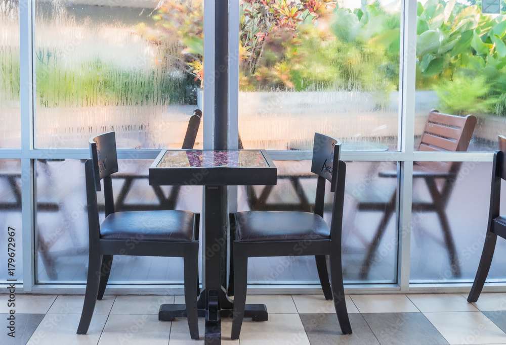 Fototapeta premium Table and chairs are located by the window.