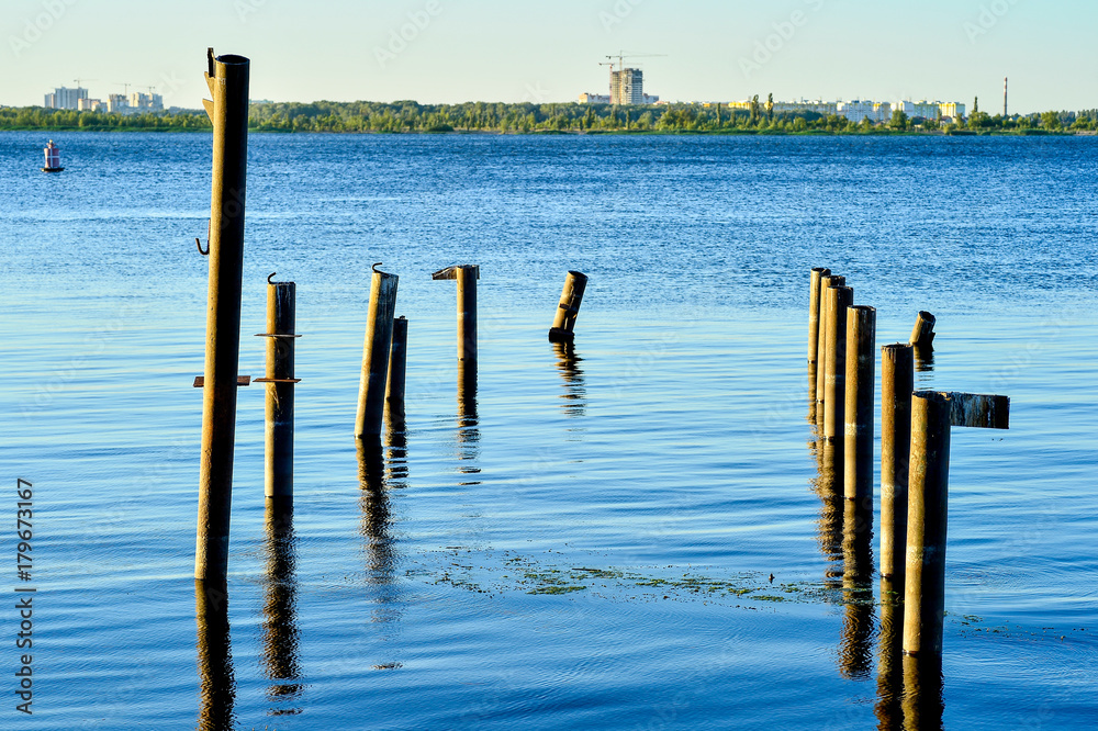 Wooden posts for the berth of boats and boats on the reservoir