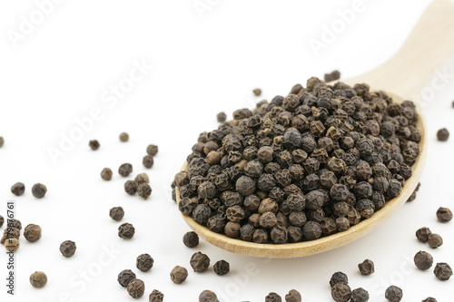 close up of black peppercorns on wooden spoon