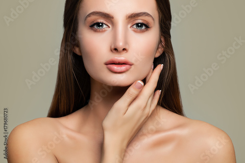 Beautiful Female Face Closeup. Spa Woman with Healthy Skin touching her Hand her Face