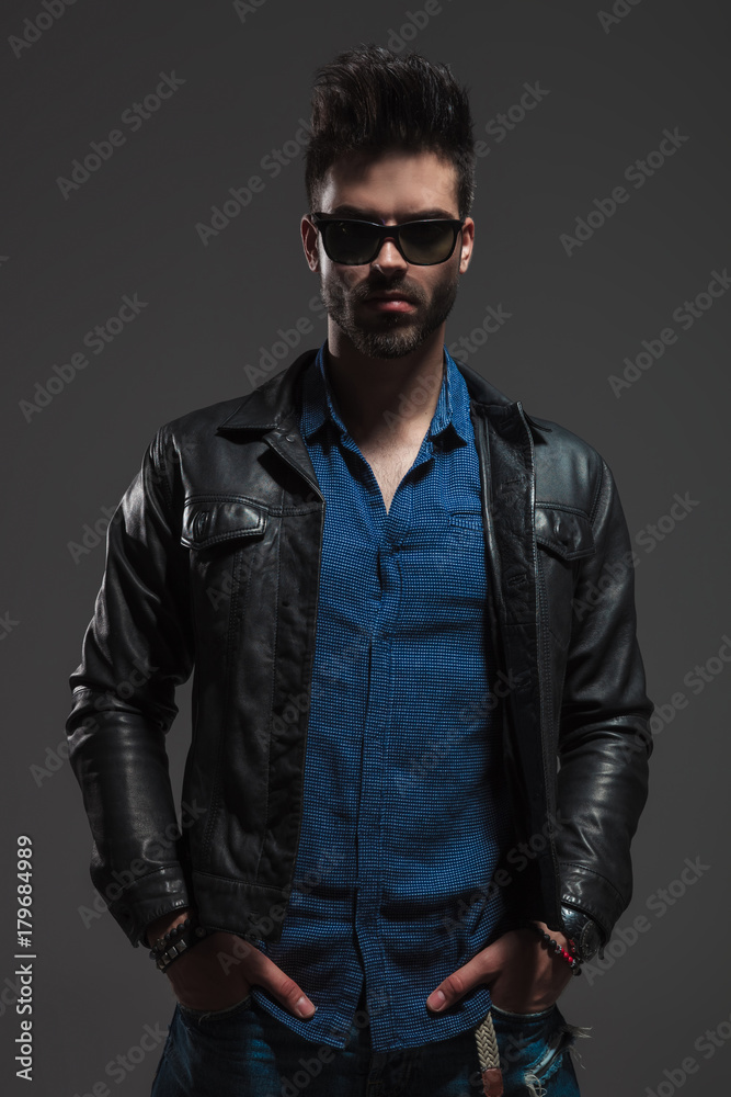 man wearing leather jacket standing with hands in pockets man wearing leather jacket standing with hands in pockets