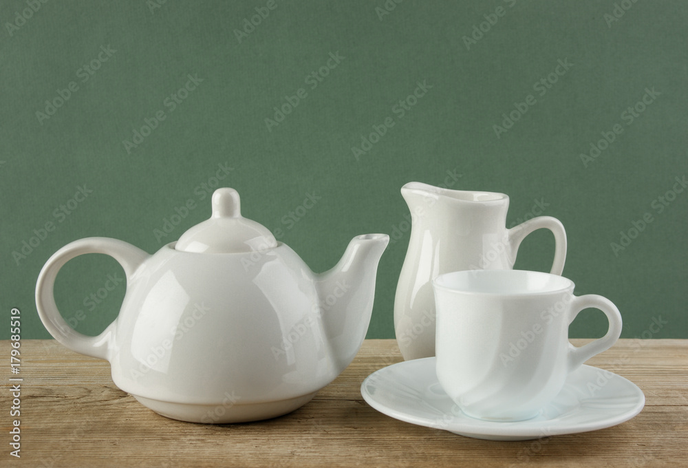white ceramic coffee set on old wooden table over green background white ceramic coffee set on old wooden table over green background