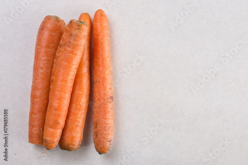 Fresh raw dirty carrot from the garden on the white marble background with copy space