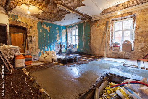 Worker is making floor from cement in the apartment during on the remodeling, renovation, extension, restoration, reconstruction and construction. Interior of upgrade apartment. photo