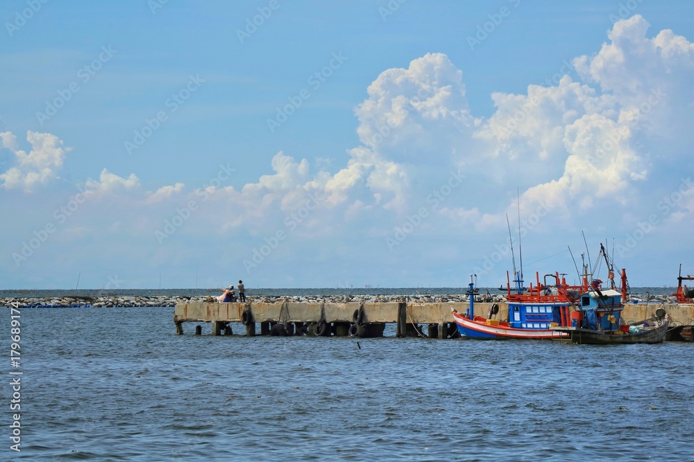 The old fisherman boat on the sea with blue sky and white cloud in the afternoon summer.