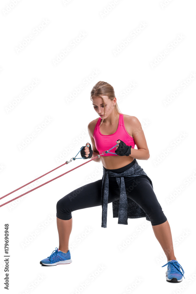 Strong woman using a resistance band in her exercise routine. Young woman performs fitness exercises on white background.