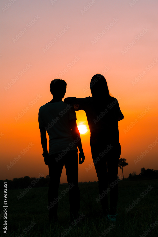 Silhouette of a couple standing on sunset.