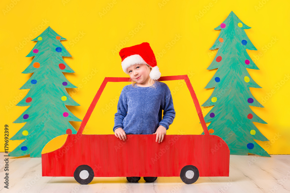 Child with Christmas hat driving a car made of cardboard. Christmas concept. New Year's holidays. Child with Christmas hat driving a car made of cardboard. Christmas concept. New Year's holidays.