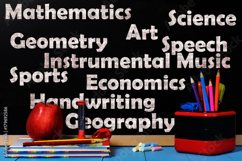 School subjects on black chalkboard with school accessories