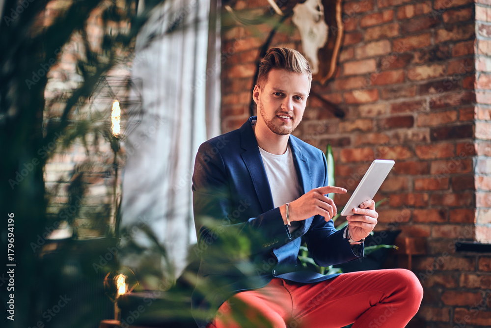 Obraz premium A man using tablet PC in a room with loft interior.