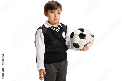 Disappointed little schoolboy with a deflated football