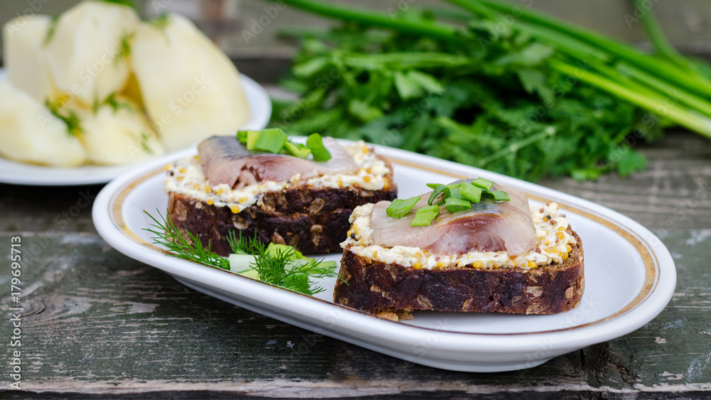 Herring, green onions, butter, French mustard and a slice of rye bread on an old wooden table. Herring, green onions, butter, French mustard and a slice of rye bread on an old wooden table.