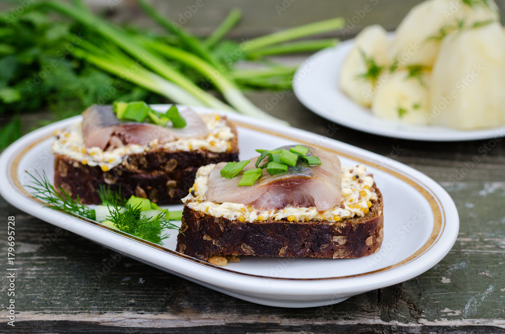 Herring, green onions, butter, French mustard and a slice of rye bread on an old wooden table.