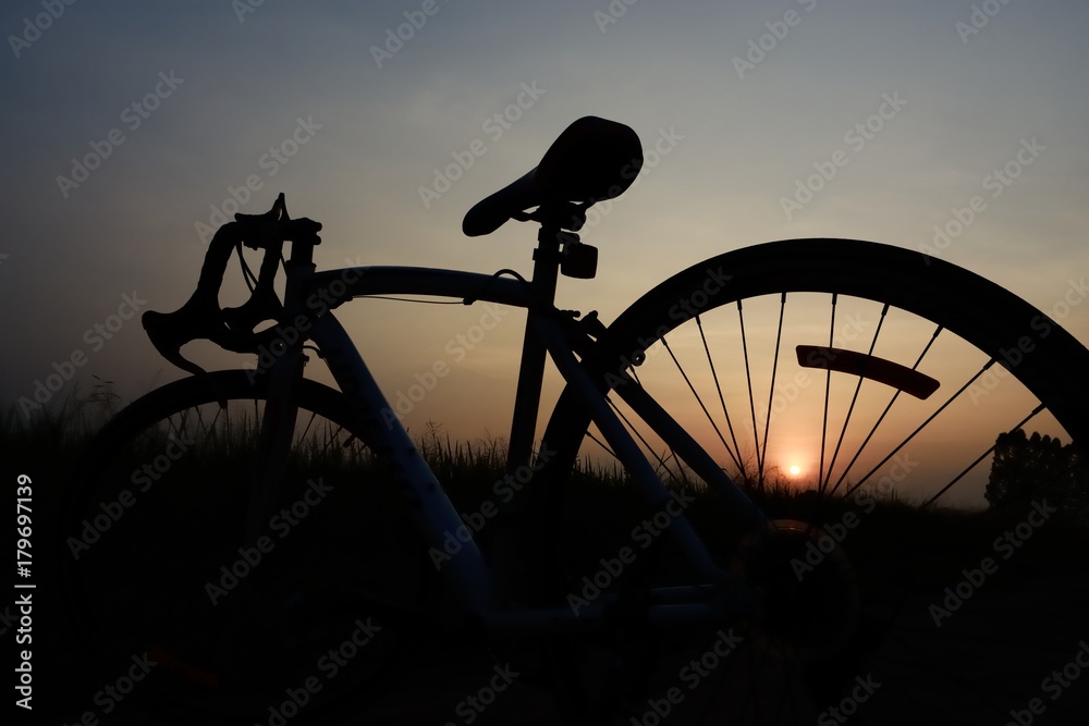 a silhouette of a bicycle against a sunset. The sun is setting behind the bicycle and the sky is a dark blue. a silhouette of a bicycle against a sunset. The sun is setting behind the bicycle and the sky is a dark blue.
