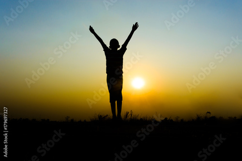 Silhouette of boy jumping on sunset background