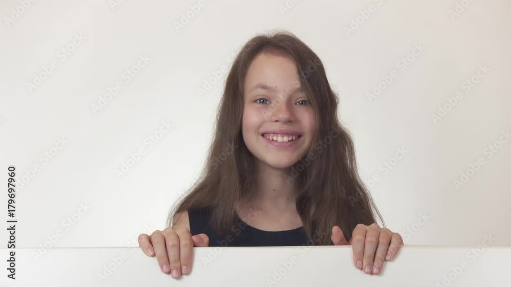 Beautiful girl teenager looks at a poster with information and happily surprised on white background stock footage video. Beautiful girl teenager looks at a poster with information and happily surprised on white background stock footage video.