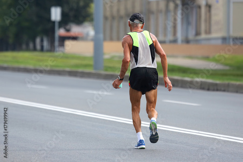 older athlete runs a marathon. © photosaint