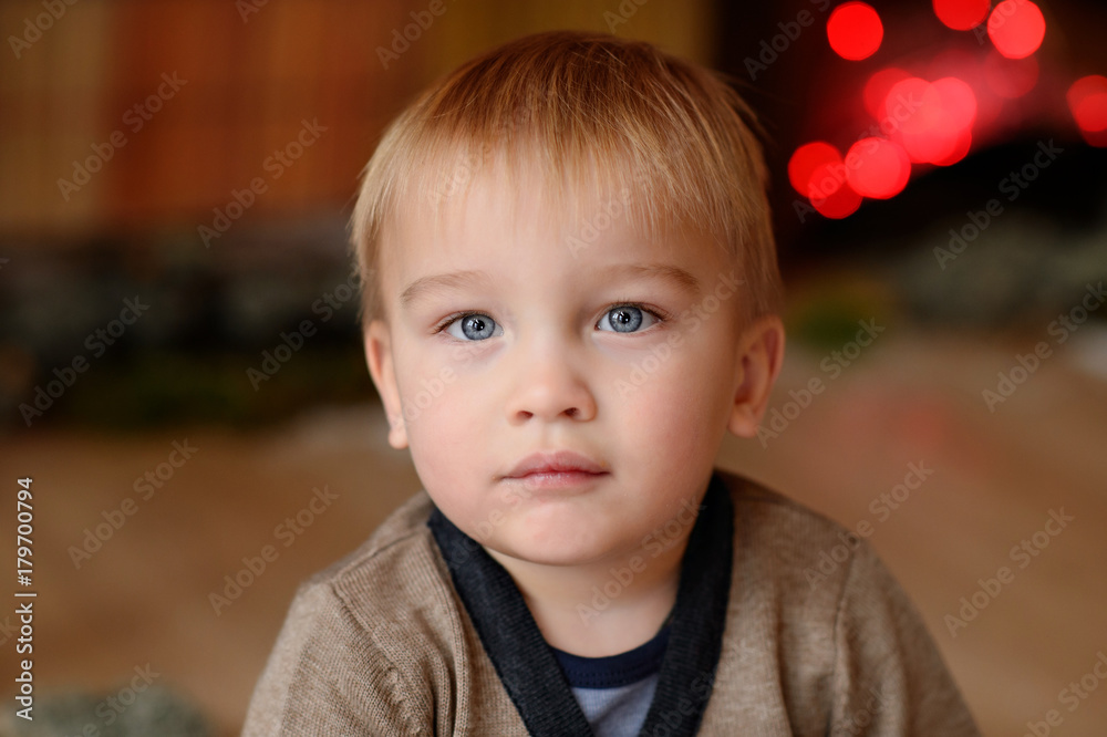 Little child near the fireplace with flowers. Merry Christmas. Happy New Year. Little child near the fireplace with flowers. Merry Christmas. Happy New Year.