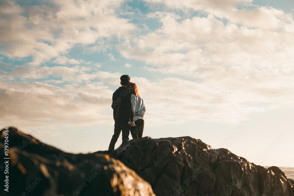 Young couple holding each other on beach at sunset