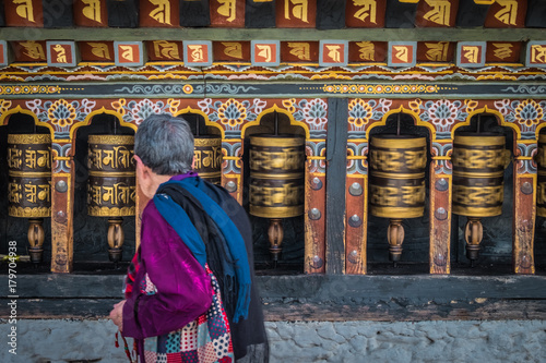 Old woman spinning prayer wheels in Thimphu, Bhutan photo