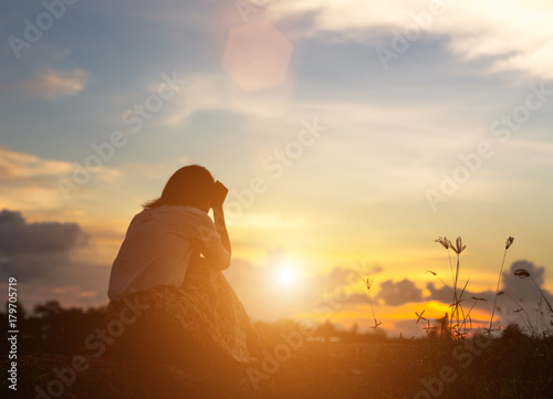 Silhouette of woman praying over beautiful sky background
