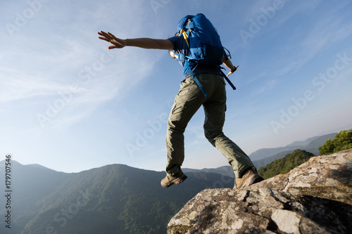 brave woman hiker walking to the cliff edge on mountain top