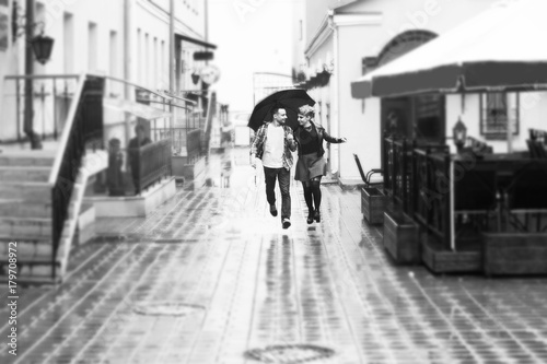 concept of love: loving couple under an umbrella walking down the street of the city.black-and-white photo in retro style