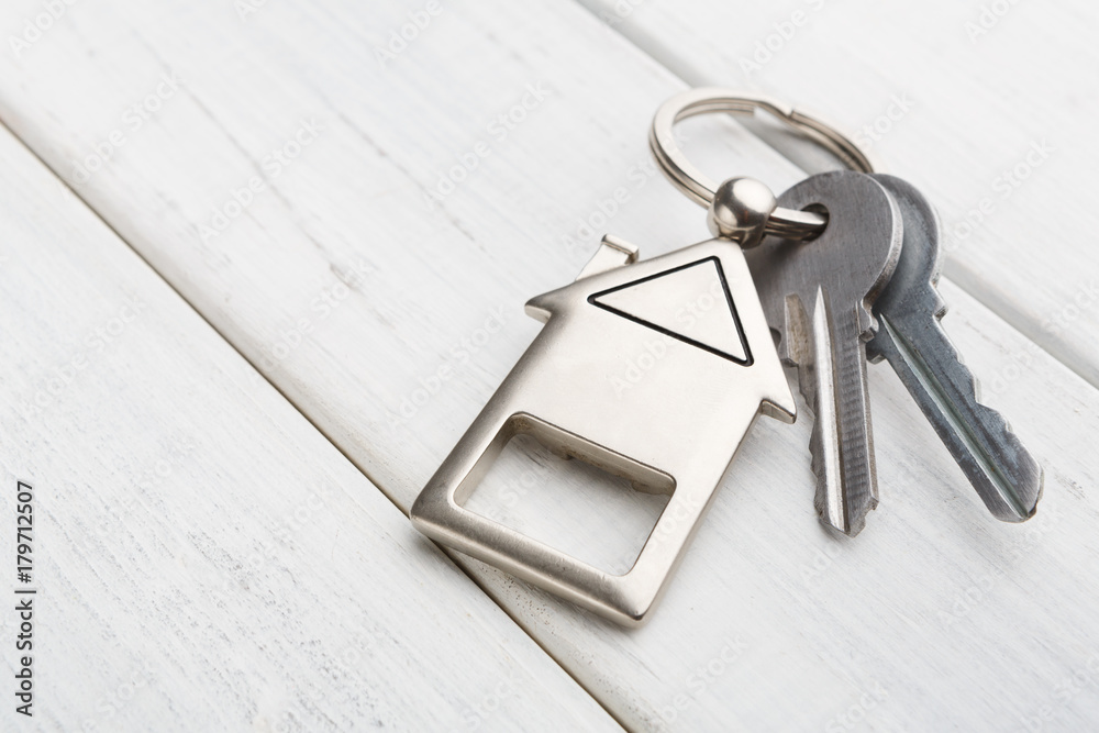 Bunch of keys with house shaped keychain on white wood Bunch of keys with house shaped keychain on white wood