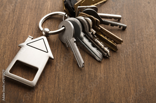 Bunch of keys with house shaped keychain on white wood photo