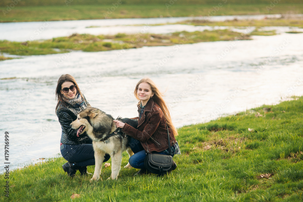 A beautiful girs are walking along the embankment. Blond hair and brown jacket. sisters A beautiful girs are walking along the embankment. Blond hair and brown jacket. sisters