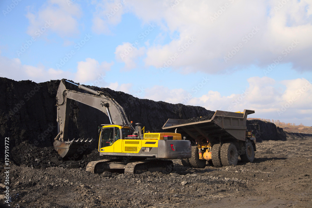 The excavator loads a mining dump truck on a coal mine.