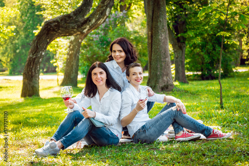 Young beautiful girls with glass of red wine in the park