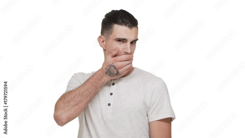 slow motion portrait of good-looking man 20s wearing casual shirt being surprised stunned covering open mouth with hand over white background closeup. Concept of emotions