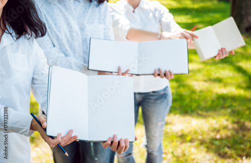 Young beautiful girls drawing the pictures in sketchbook. At the park photo