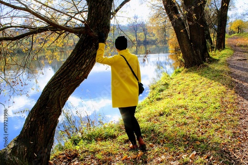 A woman in a yellow coat is standing on the shore of a pond in the estate of Count Leo Tolstoy in Yasnaya Polyana.