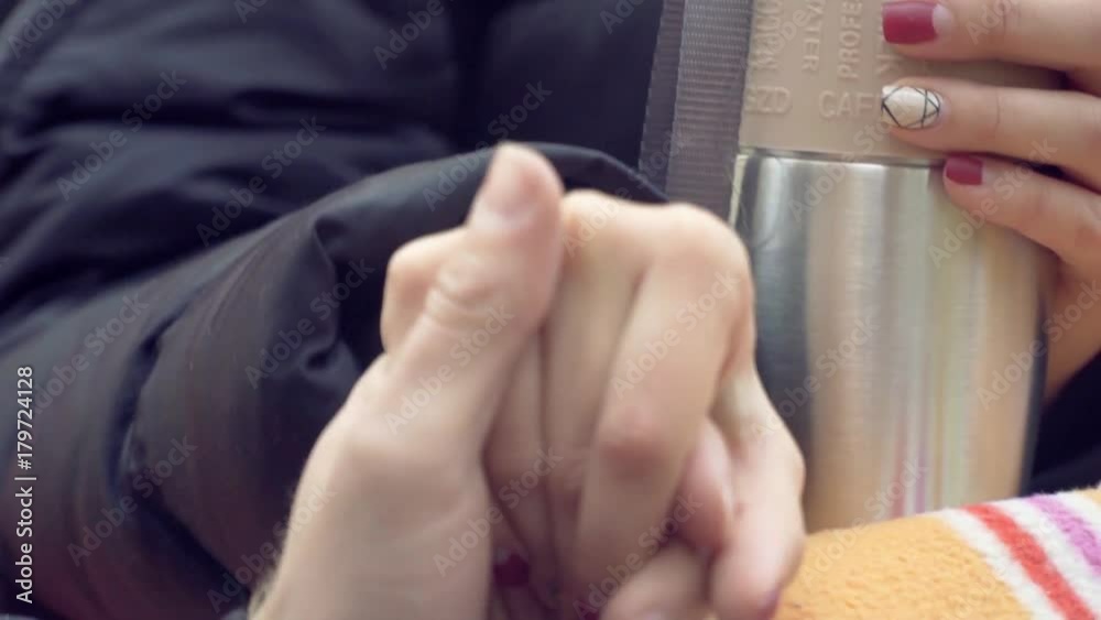 A woman with a beautiful manicure holds hands with a man and in the other hand her thermos A woman with a beautiful manicure holds hands with a man and in the other hand her thermos