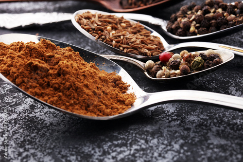 Various spices and spoons on dark table.
