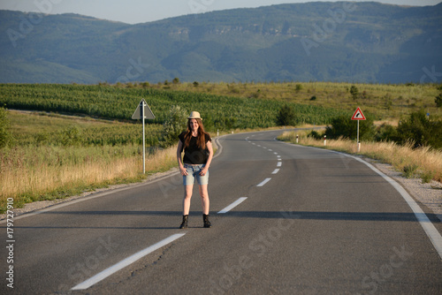 Woman Walking on the road in mountains at sunset. Lonely middle aged woman on the road