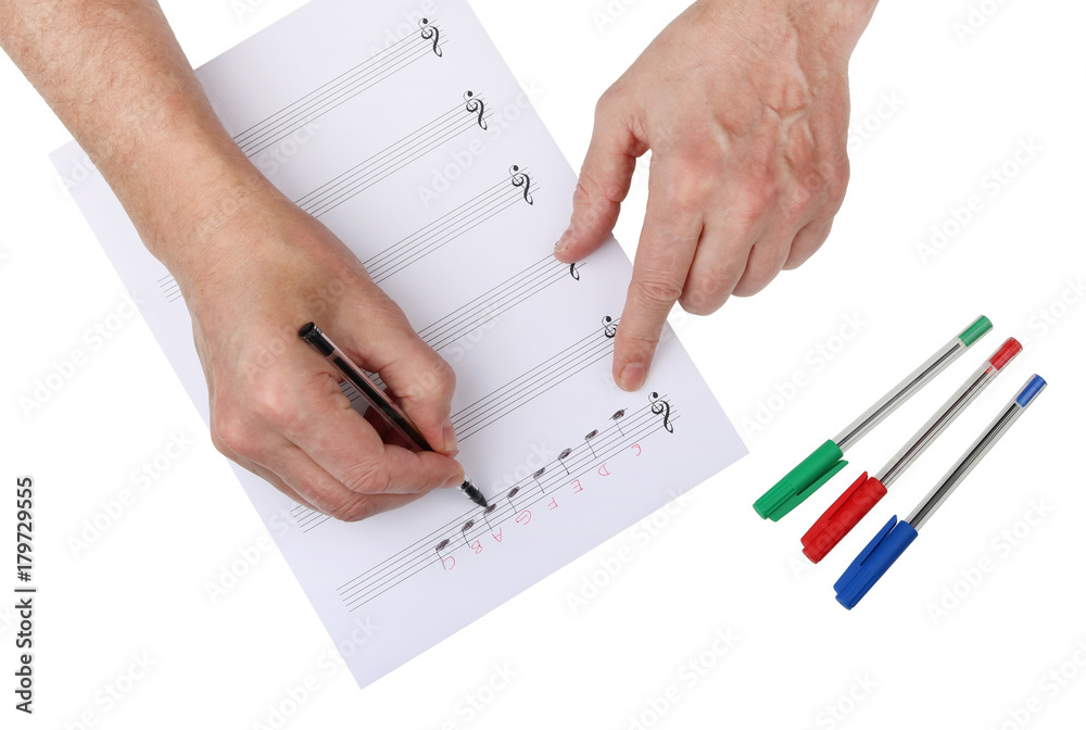 An elderly music teacher writes a scale of C major on lined sheet music paper. An elderly music teacher writes a scale of C major on lined sheet music paper.