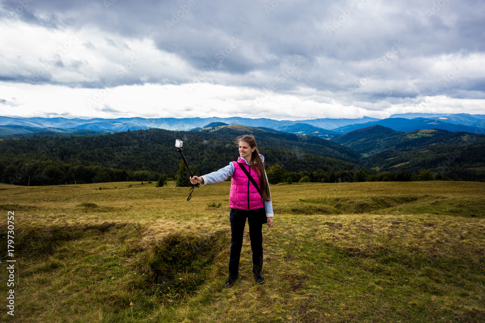 Young traveler girl on top of a hill with a beautiful view of the mountains, feeling happy, successful concept. Young girl love wild life, travel, freedom