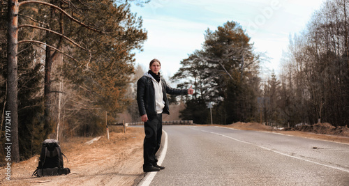 A young man is hitchhiking around the country. The man is trying