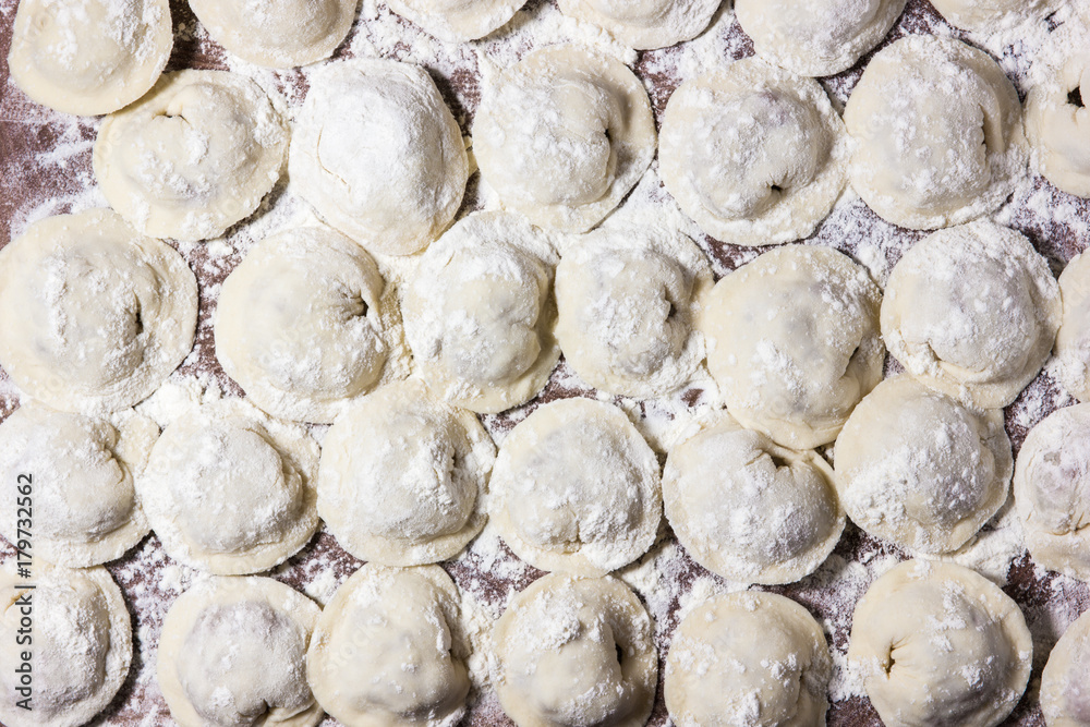 Dumplings of hand-made meat, sprinkled with flour on the table.