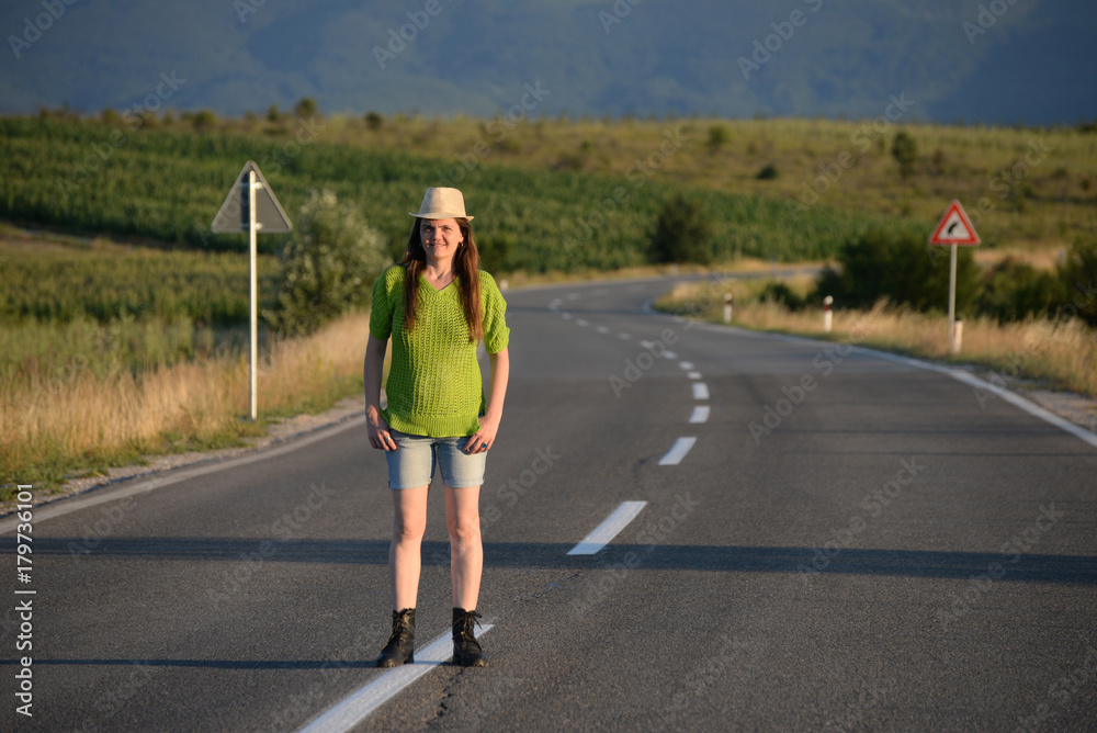 Woman Walking on the road in mountains at sunset. Lonely middle aged woman on the road Woman Walking on the road in mountains at sunset. Lonely middle aged woman on the road