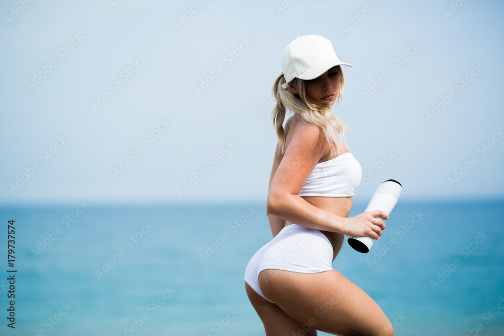 young beautiful sports girl posing with a bottle in his hand on the beach young beautiful sports girl posing with a bottle in his hand on the beach