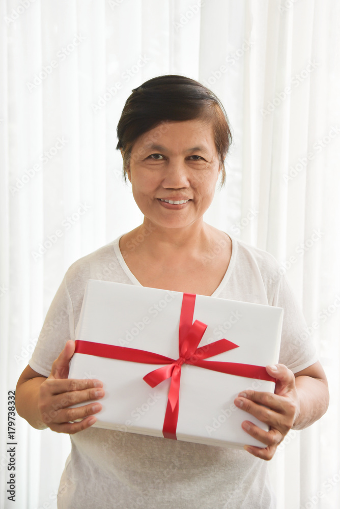 Asian elderly woman holding a white gift box. Asian elderly woman holding a white gift box.