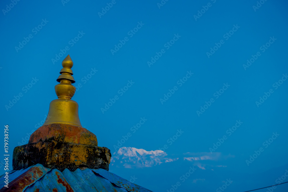 Close up of a golden structure taken in camera with a beautiful mountain view Annapurna during sunrise at Sarangkot, Nepal